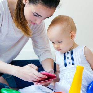 Mother and baby girl using a smartphone at home