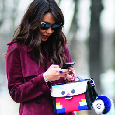 Mujer con abrigo y bolso usando su teléfono inteligente Android.