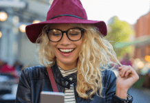 Mujer con sombrero viendo las notas de Instagram en su smartphone en medio de la calle.- Blog Hola Telcel